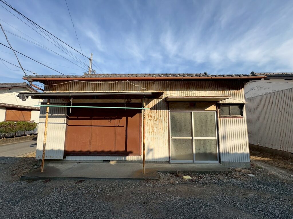 リフォーム前の外観。サビの目立つスチール扉と古い引き戸が並ぶ、築年数を感じる平屋の正面